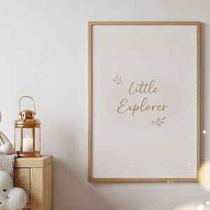 May include: A framed print with the words "Little Explorer" in a soft, elegant font. A plush bunny, a gold lantern with a lit candle, and a cloud-shaped pillow sit on a wooden cabinet, creating a cozy nursery theme.