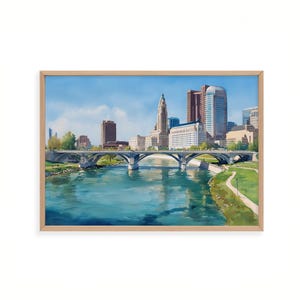 May include: A framed art print of a cityscape featuring a river, bridge, and buildings under a blue sky. The artwork showcases a detailed depiction of a city with various architectural styles, with a focus on the bridge and water.