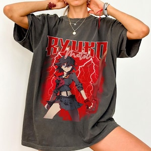 May include: Dark gray t-shirt featuring a graphic of an anime character with the text "RYUKO MATOI" in red. The design includes a red lightning bolt background and a sword. The shirt has a vintage, worn look.