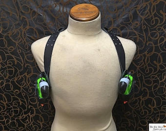 May include: A black leather shoulder holster with two green and white holsters attached. The holsters are empty.