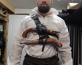 May include: A person wearing a white ruffled shirt and brown striped pants, with a black leather gun holster holding two antique pistols. The holster has a decorative silver buckle.