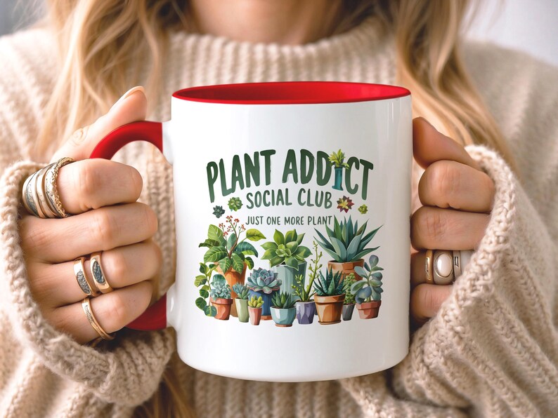May include: A white ceramic mug with a red handle and interior rim. The front features a colorful illustration of various potted succulents and houseplants with the text "PLANT ADDICT SOCIAL CLUB" and "JUST ONE MORE PLANT" printed in green.
