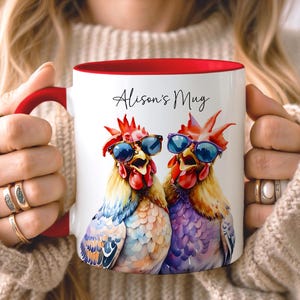 May include: White ceramic mug with a red interior and handle, featuring a watercolour illustration of two roosters wearing sunglasses. The mug is labelled "Alison's Mug" in script.