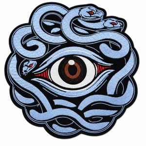 Könnte beinhalten: Ein kreisförmiger bestickter Aufnäher mit einem zentralen menschlichen Auge mit brauner Iris und weißer Sklera, umgeben von hellblauen Schlangen mit roten Augen. Das Design ist auf schwarzem Grund mit einem dicken schwarzen Rand gehalten.