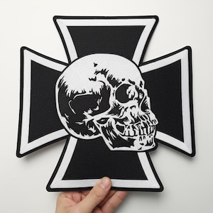 May include: A black and white patch featuring a skull design centered on a Maltese cross. The skull is detailed with shading and highlights, and the cross has a white border. The patch is likely for clothing or accessories.