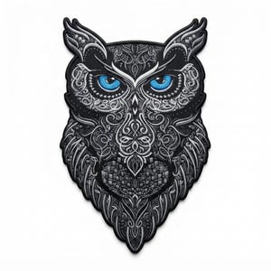 May include: An embroidered patch shaped like an owl head, featuring intricate black and white filigree patterns throughout the feathers. The owl has two prominent, bright blue eyes that stand out against the monochromatic, detailed embroidery.