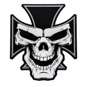 May include: A black and white embroidered patch featuring a stylized skull with a wide, toothy grin centered over a black iron cross shape. The design uses high-contrast white thread for the skull details against a solid black background.