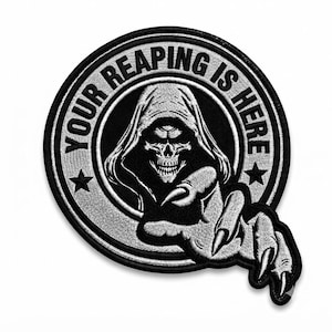 May include: A circular embroidered patch featuring a black and white design of a hooded skeleton figure with a third eye. The text "YOUR REAPING IS HERE" is arched along the top border, flanked by two stars. A skeletal hand reaches forward.