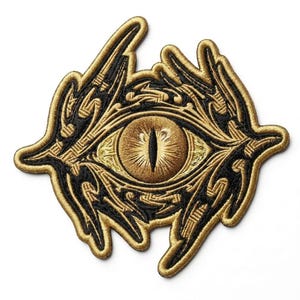 May include: An embroidered patch featuring a central eye with a vertical black pupil surrounded by a golden iris. The surrounding area consists of intricate, swirling black and gold thread patterns that form an irregular, organic shape.