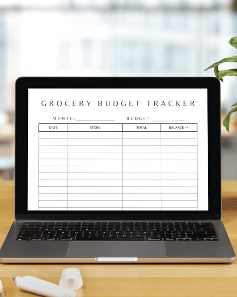 K&ouml;nnte beinhalten: Ein Laptop zeigt eine Vorlage f&uuml;r einen "Lebensmittel-Budget-Tracker". Der schwarze Bildschirm zeigt ein wei&szlig;es Formular mit Feldern f&uuml;r Monat, Budget, Datum, Gesch&auml;ft, Gesamtbetrag und Saldo. Der Laptop steht auf einer Holzoberfl&auml;che.