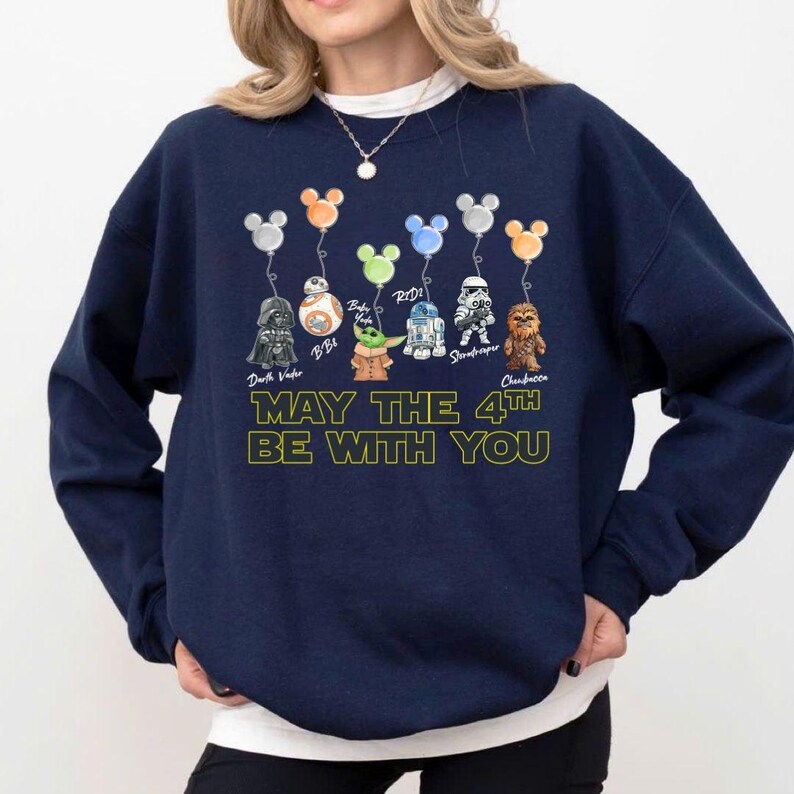 May include: Navy blue sweatshirt with Star Wars characters as balloons, including Darth Vader, BB-8, and Chewbacca. The text "MAY THE 4TH BE WITH YOU" is printed in yellow. The balloons have Mickey Mouse ears.