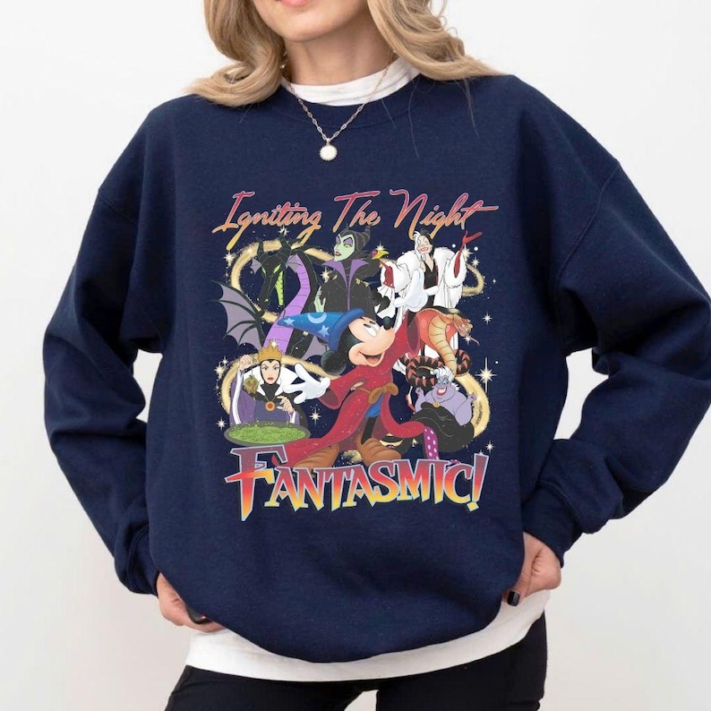 Puede incluir: Sudadera azul marino con un gr&aacute;fico colorido de personajes de Disney, incluyendo Mickey Mouse y varios villanos. El dise&ntilde;o incluye el texto "Igniting The Night" y "FANTASMIC!" en una fuente vibrante y estilizada. Un estilo c&oacute;modo e informal.