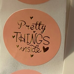 May include: Two pink round stickers with gold foil lettering that says "Pretty Things inside" with small hearts around the text.
