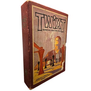 Könnte beinhalten: Vintage TwixT Brettspielbox. Die Box ist tiefrot mit dem Spieltitel in großen schwarzen Buchstaben. Das Box-Artwork zeigt eine Männersilhouette und abstrakte Spielsteine in Orange und Schwarz. Der Text lautet "Ingenious New Strategy Game for Two."