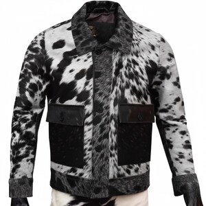K&ouml;nnte beinhalten: Schwarz-wei&szlig;e Kuhfelljacke mit Knopfleiste, zwei Vordertaschen und einem Kragen. Die Jacke hat ein geflecktes Muster und besteht aus einem strukturierten Material.