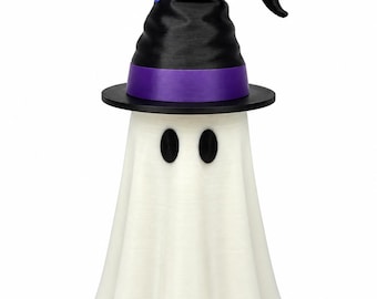 Puede incluir: Una figura de fantasma blanco que lleva un sombrero de bruja negro con una banda morada. El fantasma tiene dos ojos ovalados negros y una pajita de colores del arcoíris que sobresale de la parte superior del sombrero con textura vertical.