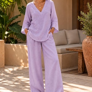 Peut inclure: Un ensemble deux pièces lavande composé d'une tunique à manches longues avec un col en V et d'un pantalon assorti à jambes larges. Le vêtement présente un tissu texturé, des poches latérales sur le pantalon et une coupe décontractée.