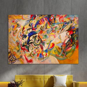 Puede incluir: Impresión de arte abstracto con una vibrante composición de formas y colores. La obra de arte muestra una disposición dinámica de azules, rojos, amarillos y verdes, creando una sensación de movimiento. El cuadro está sobre un sofá amarillo.
