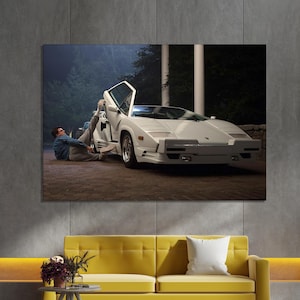 May include: A canvas print showing a white sports car with an open door. A person is reclining near the car. The print hangs above a yellow sofa in a contemporary living room, creating a stylish decor.