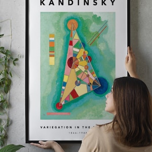 Può includere: Una stampa artistica incorniciata con una composizione geometrica astratta e colorata di Kandinsky. L'opera, intitolata "Variegation in the...", presenta una forma triangolare centrale con cerchi e linee di vari colori. La stampa è tenuta da una persona.