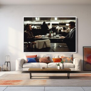 May include: A large framed print of a scene from a film hangs above a white sofa with colorful throw pillows. A wooden coffee table and a patterned rug are in front of the sofa. A tall window and decorative items complete the room.