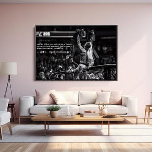 May include: Black and white framed print of a mixed martial arts fighter holding championship belts above his head. The print includes a quote by Conor McGregor. The image is displayed above a white sofa.