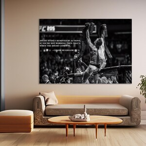 May include: Black and white print of a victorious athlete holding up championship belts. The image includes the quote "Doubt is only removed by actions. If you're not working then that's when the doubt comes in." by Conor McGregor.