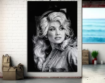 May include: Black and white portrait of a woman with voluminous, wavy blonde hair, wearing a denim shirt and large hoop earrings. The image is a close-up, focusing on her face and upper body. The background is dark, emphasizing the subject.