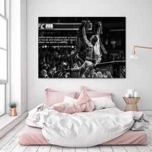 May include: Black and white print of a victorious athlete holding up championship belts. The image includes text that reads "Doubt is only removed by actions. If you're not working then that's when the doubt comes in." - Conor McGregor.