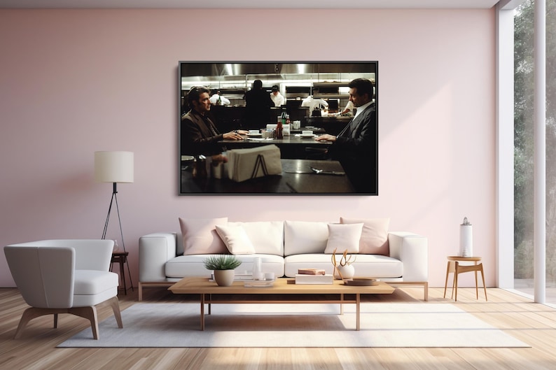 May include: A framed print of a scene from a film, depicting two people seated at a table in a restaurant. The background shows a kitchen with chefs. The room is decorated with a white sofa, a wooden coffee table, and a white armchair.
