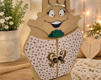 May include: A decorative storage cabinet shaped like a character with a smiling face, featuring a tan paper-like finish, two doors with a small red floral pattern, gold-toned hardware, and a single bottom drawer with a matching gold-toned knob.