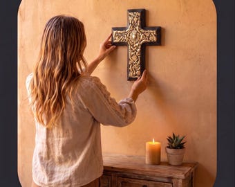 May include: A black wooden cross featuring intricate gold-colored relief carvings of floral motifs and a central heart emblem. The cross is mounted on a wall, displaying detailed craftsmanship with a dark frame and a textured, metallic-finished interior.