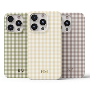 Puede incluir: Tres fundas para teléfono con un estampado de cuadros vichy en verde, crema y topo. Cada funda tiene diferentes iniciales doradas en la parte inferior. Las fundas tienen un recorte para la cámara y están diseñadas para un smartphone.