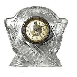 Può includere: Un orologio da mensola in vetro trasparente tagliato con quadrante dorato. L'orologio presenta un motivo geometrico decorativo e una parte superiore curva. Il quadrante ha numeri e lancette nere, con il marchio "Westclox" in basso.