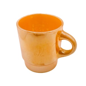 Op de afbeelding: Een glanzende, iriserende oranje mok met een gladde, reflecterende afwerking. De mok heeft een cilindrisch lichaam dat iets naar de basis toe taps toeloopt, een brede ronde rand en een gebogen handvat aan de zijkant, alles in een perzik-oranje tint.
