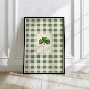 Puede incluir: Impresi&oacute;n art&iacute;stica enmarcada con un tr&eacute;bol verde sobre un fondo crema, sobre un patr&oacute;n de cuadros verdes y blancos. La obra de arte est&aacute; en un marco negro, ideal para la decoraci&oacute;n de paredes. La impresi&oacute;n es de Glee & Paper Studio.