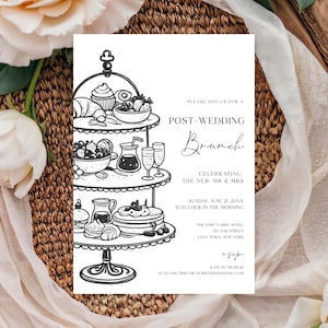 May include: Black and white post-wedding brunch invitation. The invitation features a tiered serving stand with illustrations of pastries, fruit, and drinks. Text includes "Post-Wedding Brunch" and event details. The invitation is surrounded by flowers and fabric.
