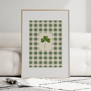 Puede incluir: Impresi&oacute;n art&iacute;stica enmarcada con un tr&eacute;bol verde sobre un fondo beige, sobre un patr&oacute;n de cuadros verdes y blancos. La obra de arte se muestra en un marco dorado, adecuada para la decoraci&oacute;n del hogar.