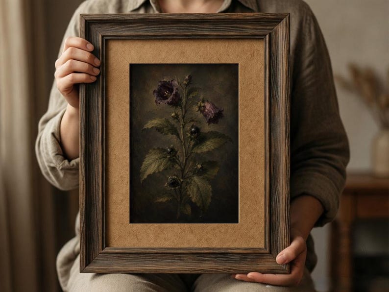 May include: A rectangular dark brown wooden frame containing a botanical print of a dark purple flower with green leaves. The artwork features a moody, shadowed background and is set within a light brown mat board, creating a high-contrast display.
