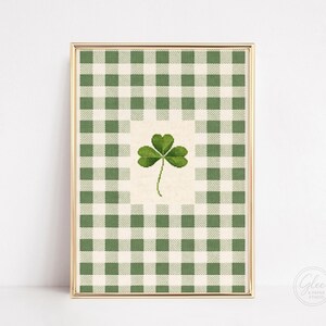 Puede incluir: Impresi&oacute;n enmarcada con un tr&eacute;bol verde sobre un fondo crema, sobre un patr&oacute;n de cuadros verdes y blancos. La obra est&aacute; en un marco dorado, ideal para decoraciones del D&iacute;a de San Patricio. Tama&ntilde;o aproximado: 20 x 30 cm.