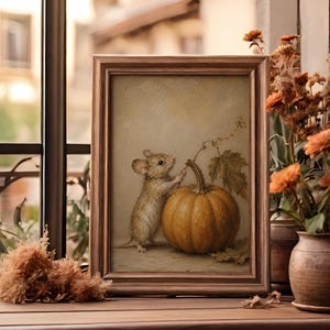 Peut inclure: Une peinture encadr&eacute;e repr&eacute;sentant une petite souris brune debout &agrave; c&ocirc;t&eacute; d'une grosse citrouille orange avec une tige et une feuille vertes. L'&oelig;uvre est r&eacute;alis&eacute;e dans une palette de couleurs douces et att&eacute;nu&eacute;es avec des coups de pinceau visibles.