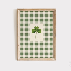 Puede incluir: Arte de pared enmarcado con un fondo de patr&oacute;n de cuadros verdes y blancos y un tr&eacute;bol en el centro. El tr&eacute;bol es de color verde vibrante, sobre un fondo crema. El marco es de madera clara, a&ntilde;adiendo un toque r&uacute;stico.
