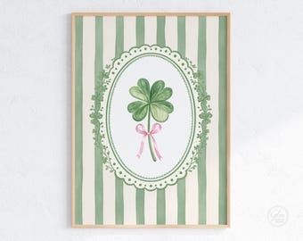May include: A framed watercolor print featuring a four-leaf clover with a pink ribbon, set against a green and white striped background. The clover is inside an oval frame with floral accents. The frame is made of wood.