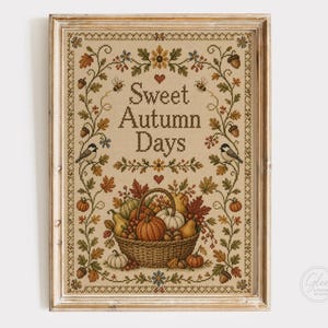Puede incluir: Un bordado en punto de cruz enmarcado con el texto Sweet Autumn Days en letras marrones. El diseño incluye una cesta central llena de calabazas, calabacines y hojas de otoño, rodeada por un borde de enredaderas, bellotas y pájaros.