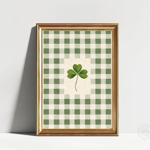 Puede incluir: Una impresi&oacute;n enmarcada con un tr&eacute;bol verde sobre un fondo crema, sobre un patr&oacute;n de cuadros verdes y blancos. La impresi&oacute;n est&aacute; en un marco dorado, creando una pieza cl&aacute;sica y decorativa.