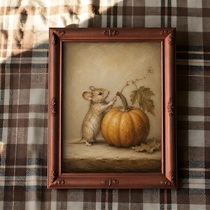 Peut inclure: Une peinture encadr&eacute;e repr&eacute;sentant une petite souris brune debout &agrave; c&ocirc;t&eacute; d'une citrouille orange ronde. La souris tend la patte vers une fine tige attach&eacute;e au p&eacute;doncule de la citrouille. L'&oelig;uvre est dans un cadre d&eacute;coratif couleur cuivre.