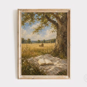 May include: A framed landscape painting depicting an open golden wheat field under a blue sky with clouds. An open book rests on a white cloth spread beneath a large tree in the foreground. The scene features hay bales in the distance.