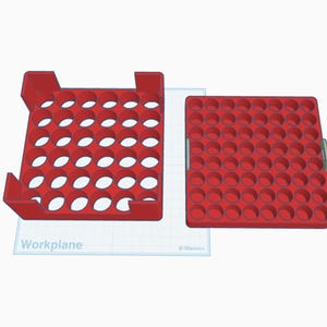May include: Red plastic organizer with multiple circular openings, designed to hold small items. The organizer is composed of two parts, one with a handle and the other with a raised frame. The word "Workplane" is visible on the white surface.