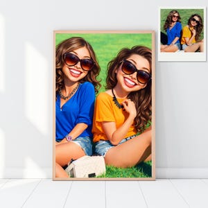 May include: A framed digital art print featuring two smiling women wearing sunglasses, sitting on grass. One wears a blue top, the other an orange top. Both are wearing denim shorts and jewelry. A smaller image of the same scene is in the upper right corner.