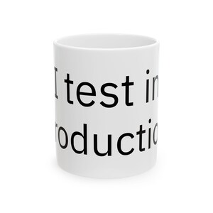 May include: White ceramic mug with the text "I test in production" printed in black. The mug is cylindrical and has a simple, clean design, suitable for coffee, tea, or other beverages.